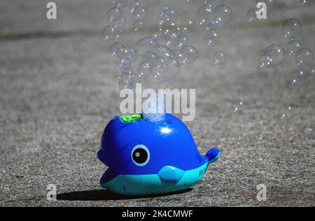 blue plastic bubble machine blows soap bubbles into the air Stock Photo