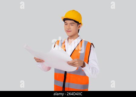 Portrait young asian man is engineer wearing helmet holding and looking blueprint with confident isolated on white background, handsome male is archit Stock Photo