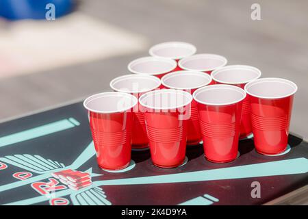 Beer pong tournament layout. Many red party cups in a nightclub full of people dancing on the dance floor in the background. Perfect for marketing and Stock Photo