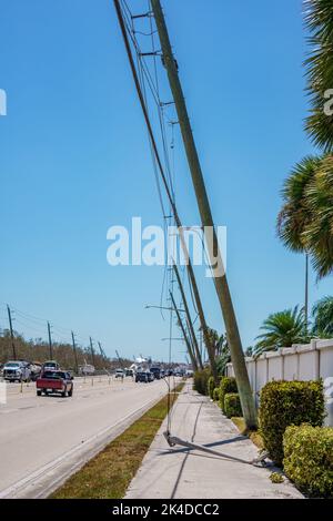Wood electric pilons tilted from Hurricane Ian heavy storm winds along San Carlos Blvd Stock Photo