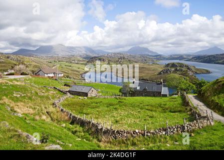 View over cottages and crofting fields by Loch Inchard, Sutherland, with mountains Foinaven, Arkle and Ben Stack visible in the distance, Scotland UK Stock Photo