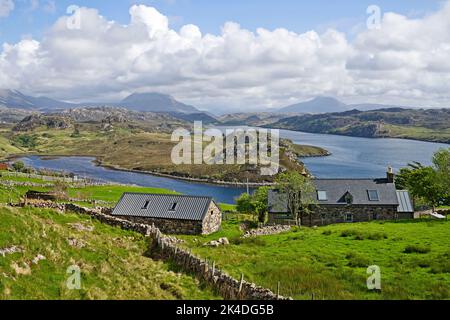 View over cottages and crofting fields by Loch Inchard, Sutherland, with mountains Foinaven, Arkle and Ben Stack visible in the distance, Scotland UK Stock Photo