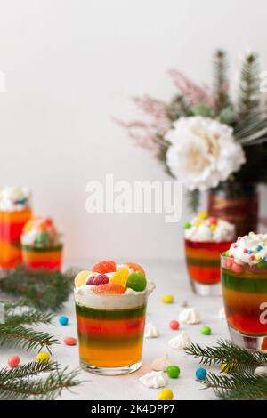 Glasses with multi-colored jelly, decorated with cream and dragees, meringues and marshmallows, Turkish delight and marmalade Stock Photo