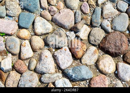Rough cobblestone pavement on the road as creative background texture. Natural stones as background. Stone pavement texture Stock Photo
