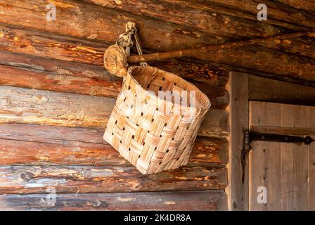 Wicker handmade basket hanging on the wall of a wooden house Stock Photo