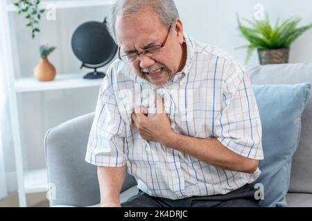 An agonizing senior man suffering from chest pain or heart attack alone ...