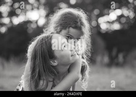 Black and white portrait of Two Happy little girls laughing and hugging at the  summer park. Stock Photo