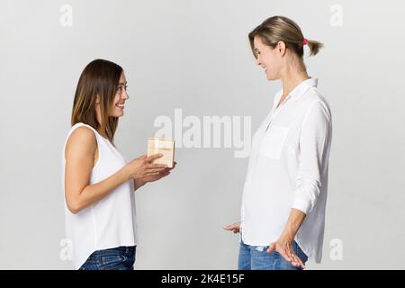 Young beautiful woman with smile gives a present to her friend. Happy birthday Stock Photo