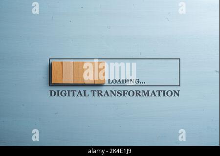 Progress bar cut into a blue wooden background with wooden blocks representing the progress loading with a Digital transformation sign under it. Stock Photo