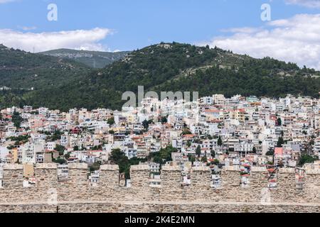 View of Kavala chaotic urban residential development on a forested hill through the battlements of the castle masonry wall on the top of the old cape Stock Photo