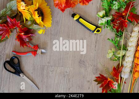 top view of sunflowers, autumn leaves, spikelets, scissors, stationery knife and other tools to create autumn decor. DIY copy space Stock Photo