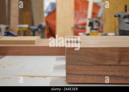 A man cuts wood on a circular saw in a joinery, band saw, holding a plank Stock Photo