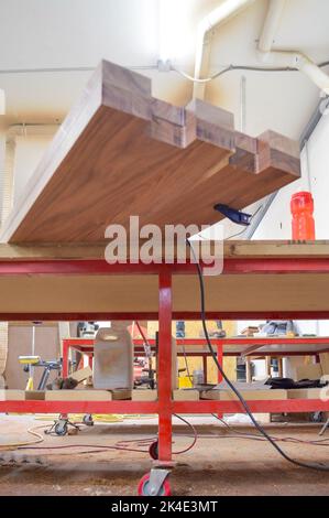 A man cuts wood on a circular saw in a joinery, band saw, holding a plank Stock Photo