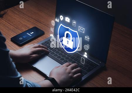 Woman checking laptop with digital security interface. Internet of things. Cybersecurity concept. Icon shield with a lock symbol. Stock Photo