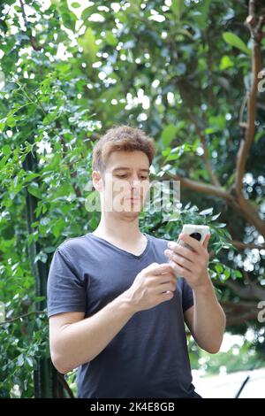 Red haired european man with freckles looking at playing with his mobile phone Stock Photo