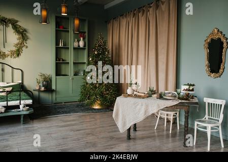 Festive set dining table in the living room against the background of Christmas tree lights Stock Photo