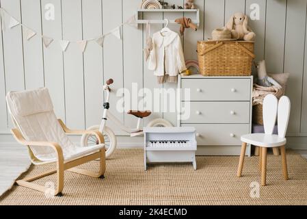 Scandinavian interior design of a playroom with modern designer furniture, a toy piano, soft toys and cute children's accessories. Stock Photo