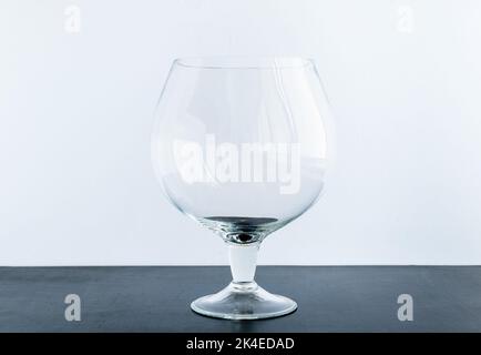Transparent cognac glass on black table and on white background. For strong alcoholic drinks Stock Photo