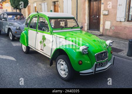 Loriol sur Drome, France - 17 September, 2022: Vintage Green Citroen 2CV with fabric hinged top and palm trees on the door. Classic car exhibition in Stock Photo