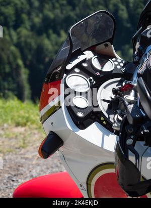 Cockipit of an adventure motorcycle, parked for a break at a pass road in the Swiss alps. Stock Photo