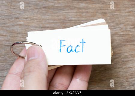 Hand hold flash card with handwriting in word fact on wood background Stock Photo