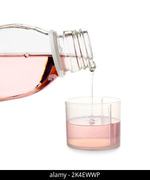 Pouring of cough syrup from bottle into cup on white background Stock Photo