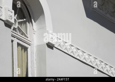 Neoclassical mansion arched wooden window on a grey stucco wall.