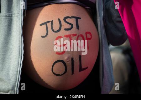 London. People protest against the oil industry and the cost of living crisis. A Pregnant woman with 'Just stop oil' written on her belly, holds a ban Stock Photo