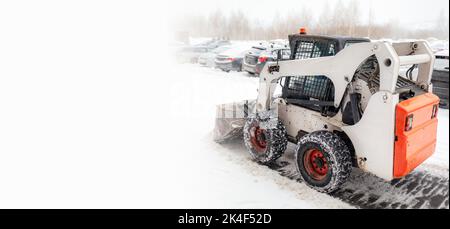 Snow clearing. Tractor clears the way after heavy snowfall. A large orange tractor removes snow from the road and clears the sidewalk. Cleaning roads Stock Photo