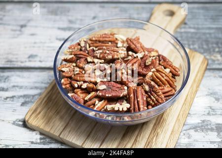 roasted walnuts in a glass bowl on a chopping board on table  Stock Photo