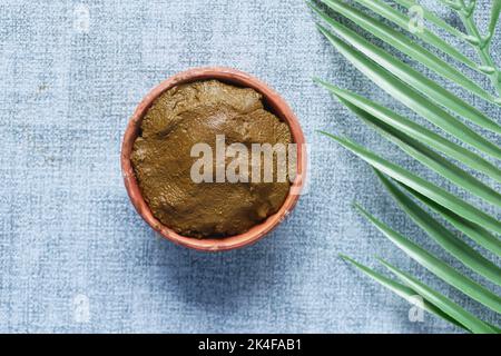 The wooden bowl with rehydrated henna on table Stock Photo