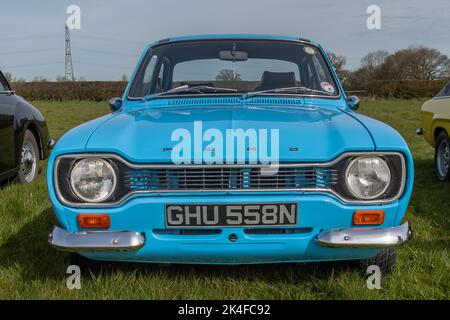 A front view of a 1974 light blue Ford Escort Mk 1 parked on grass at a meet of classic car clubs Stock Photo