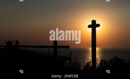 Sunset view from Westward Ho in North Devon, England. The setting sun has just passed behind the signpost. Stock Photo