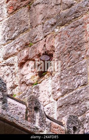 Old artillery shell in the destroyed wall of the building. Rusty projectile Stock Photo
