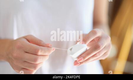 Woman holds dental white floss and package in hands closeup Stock Photo