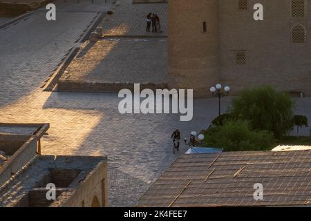 Peaceful early morning scene in Bukhara main square, cyclist next to Mir-i-Arab Madrasa Stock Photo