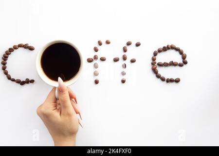 Cup of coffee and coffee beans make the word coffee, flat lay. Stock Photo