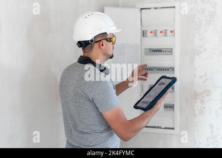 Electrical technician looking focused while working in a switchboard with fuses. Stock Photo