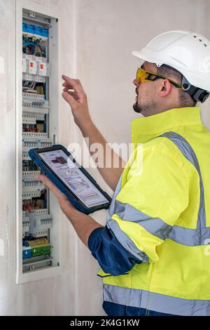 Electrical technician looking focused while working in a switchboard with fuses. Stock Photo