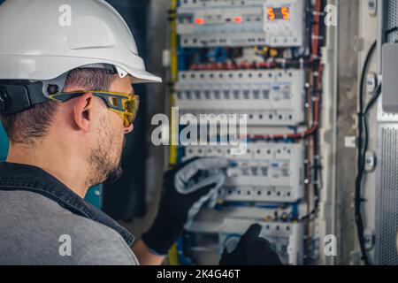 Man, an electrical technician working in a switchboard with fuses. Stock Photo