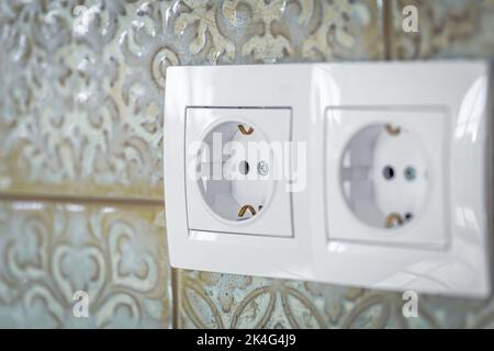 White plastic walk-through switches and sockets on a white wall. Stock Photo
