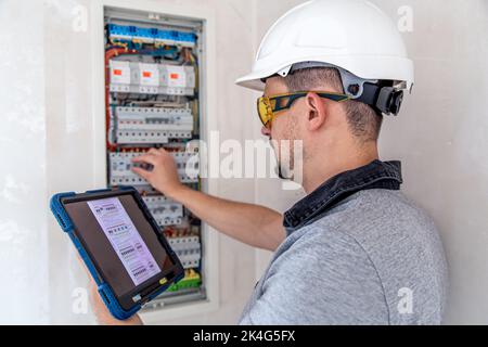 Electrical technician looking focused while working in a switchboard with fuses. Stock Photo