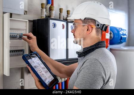 Electrical technician looking focused while working in a switchboard with fuses. Stock Photo