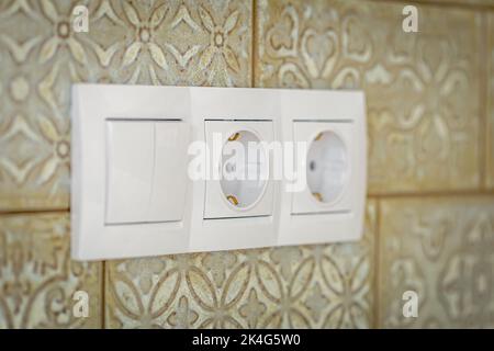 White plastic walk-through switches and sockets on a white wall. Stock Photo