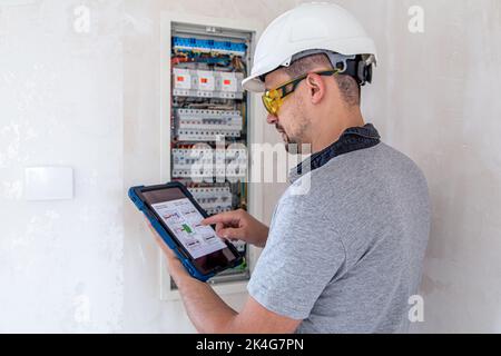 Electrical technician looking focused while working in a switchboard with fuses. Stock Photo