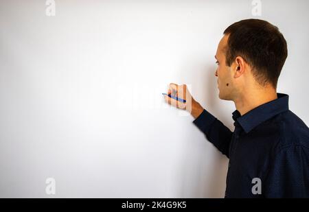 a handsome man stands at the white board and points with a pen. banner for the inscription. mockup.a man writes on a white board Stock Photo
