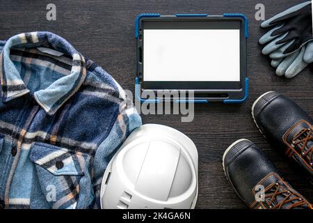 Digital tablet with layout and worker clothes, top view. Stock Photo