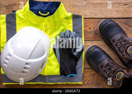 Builder uniform on wooden background, flat lay. Stock Photo
