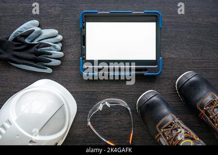 Digital tablet with layout and worker clothes, top view. Stock Photo