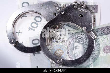 Police handcuffs and banknotes in Polish currency. The concept of economic crime in Poland. Banknotes of Polish zlotys. Stock Photo
